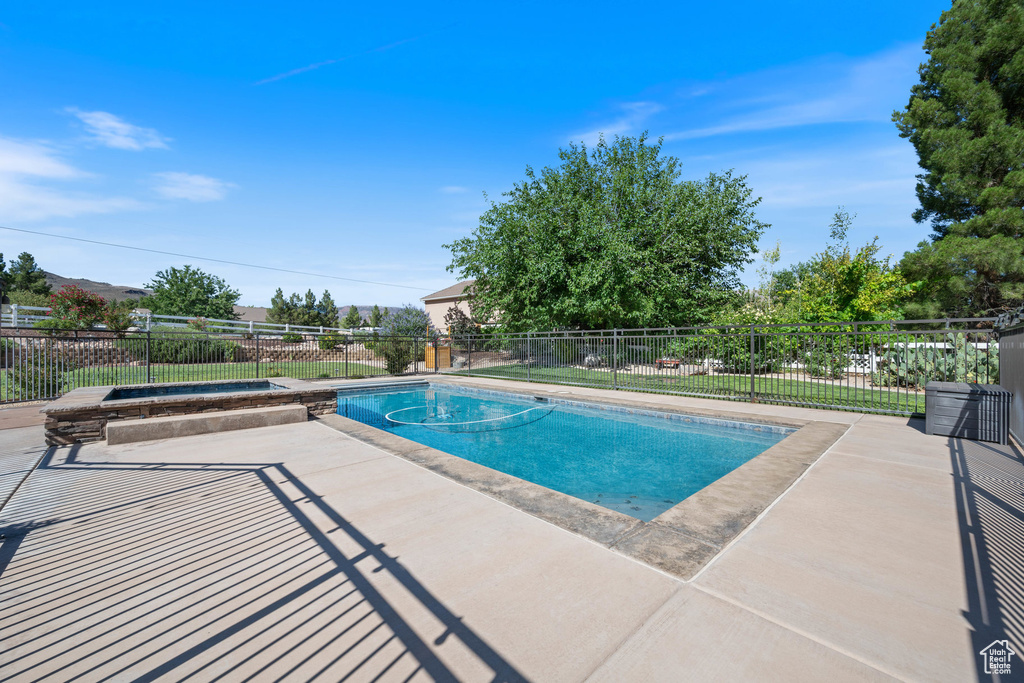View of pool with a patio and an in-ground hot tub