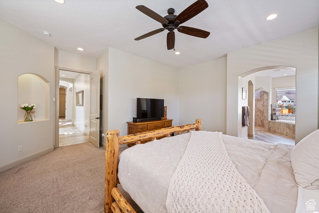 Bedroom featuring arched walkways, recessed lighting, light carpet, and a ceiling fan