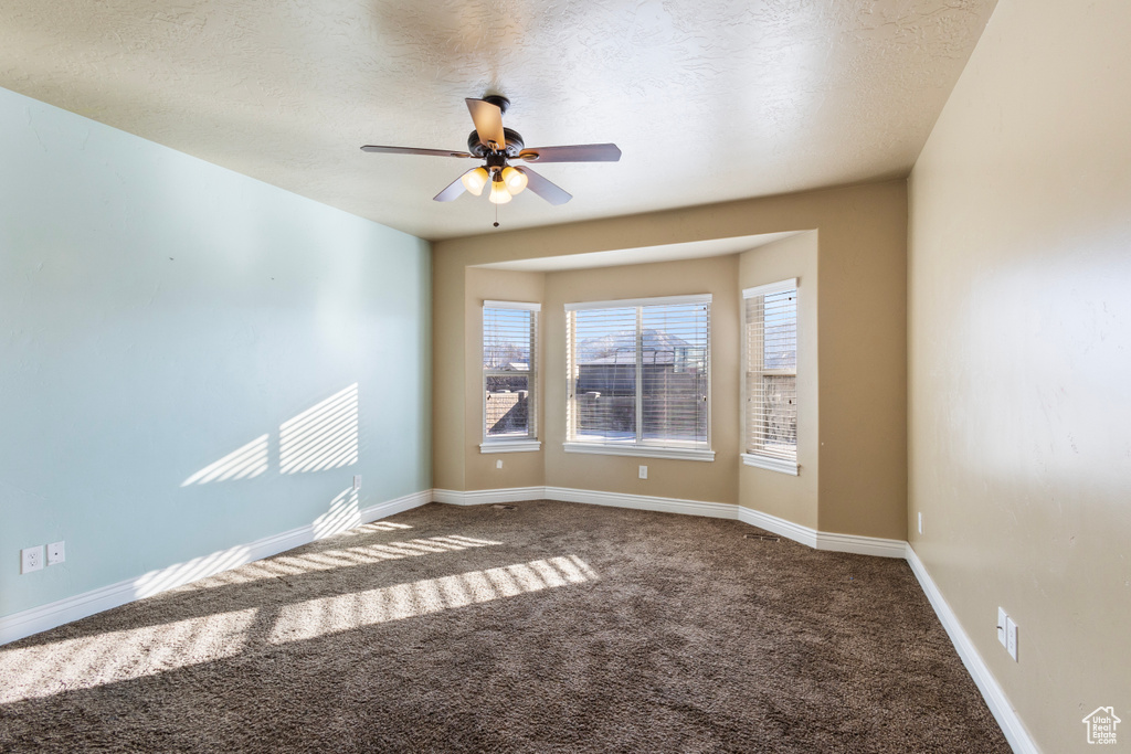 Carpeted spare room with a textured ceiling and ceiling fan