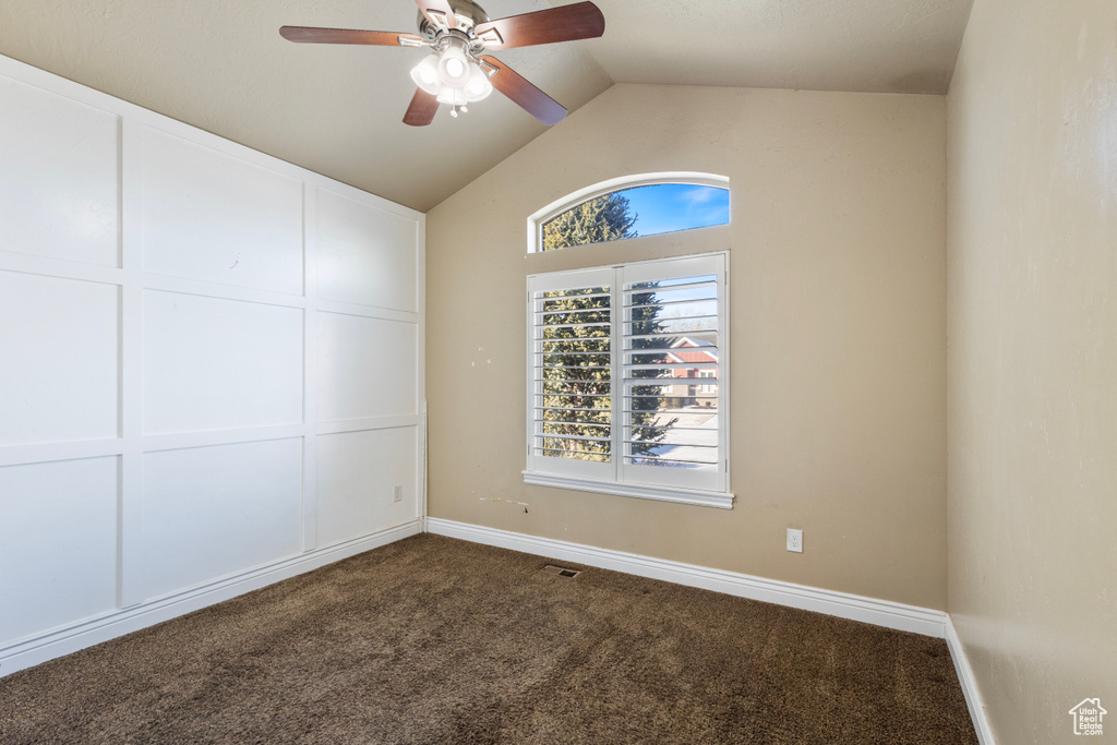 Carpeted spare room with ceiling fan, lofted ceiling, and a wealth of natural light