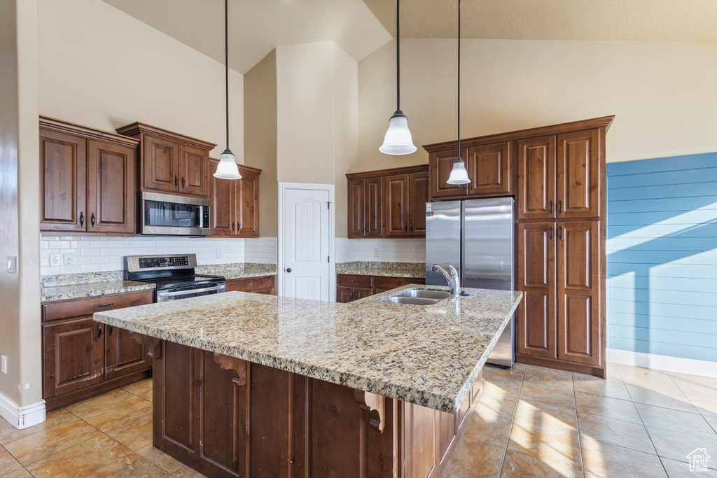 Kitchen featuring sink, hanging light fixtures, an island with sink, and appliances with stainless steel finishes