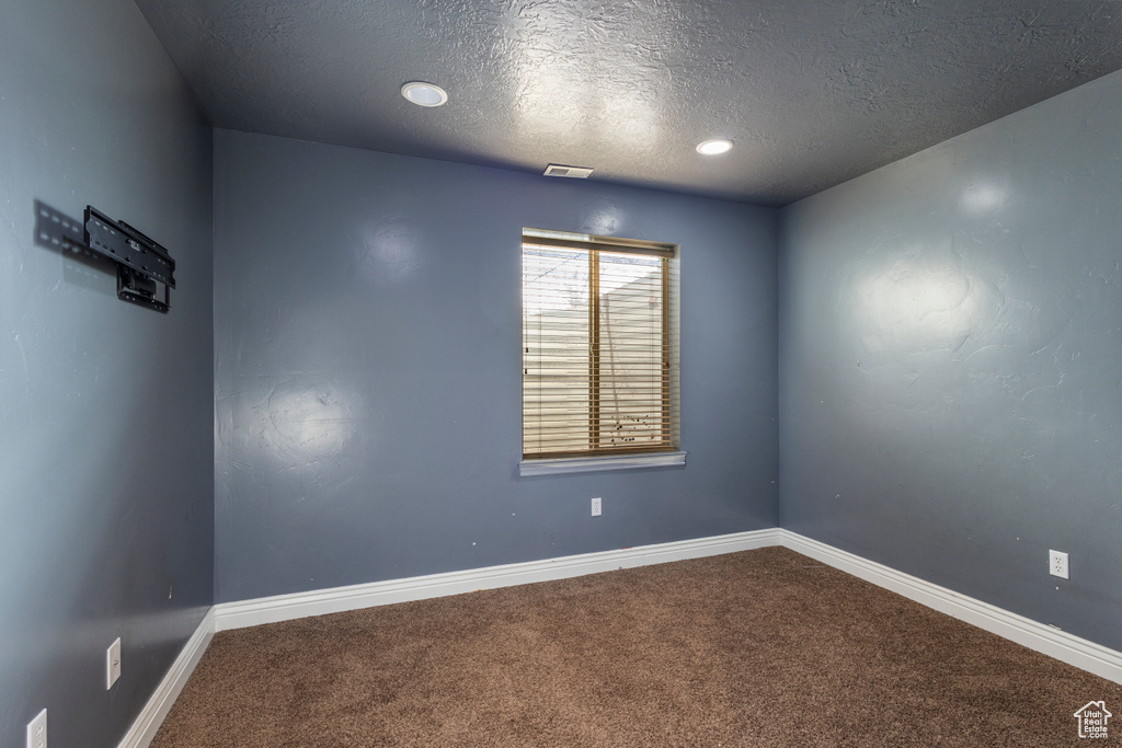 Carpeted empty room with a textured ceiling