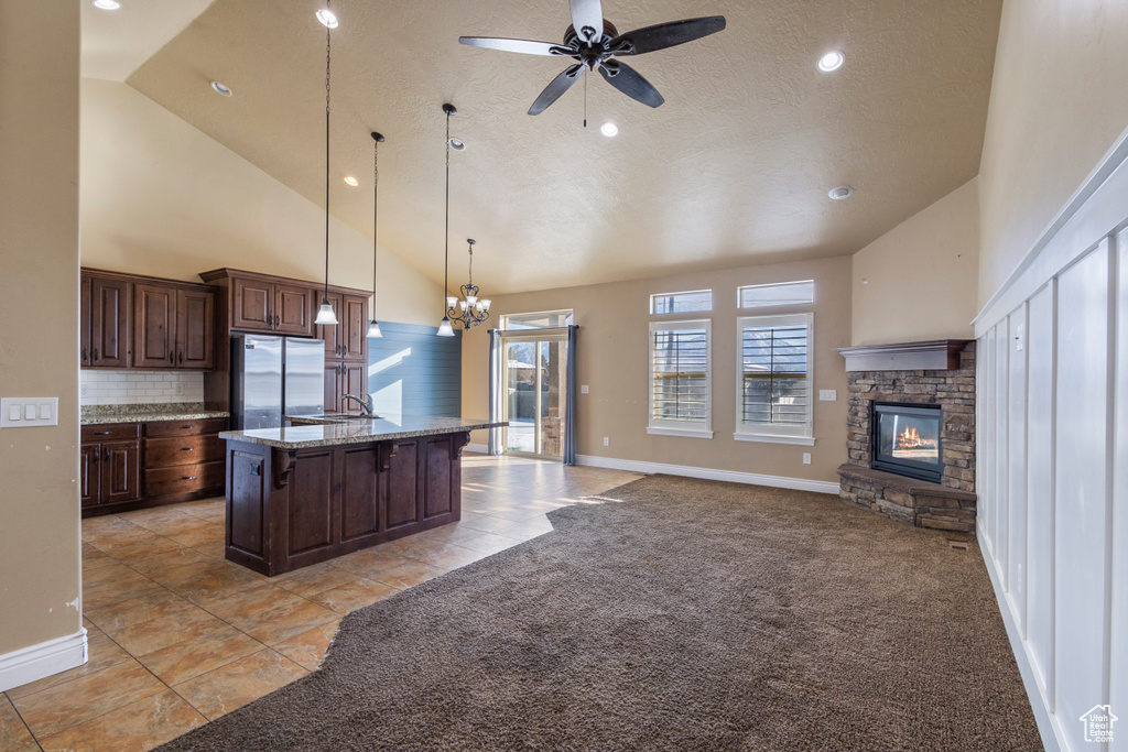 Kitchen featuring pendant lighting, stainless steel refrigerator, a kitchen island with sink, a kitchen breakfast bar, and light colored carpet