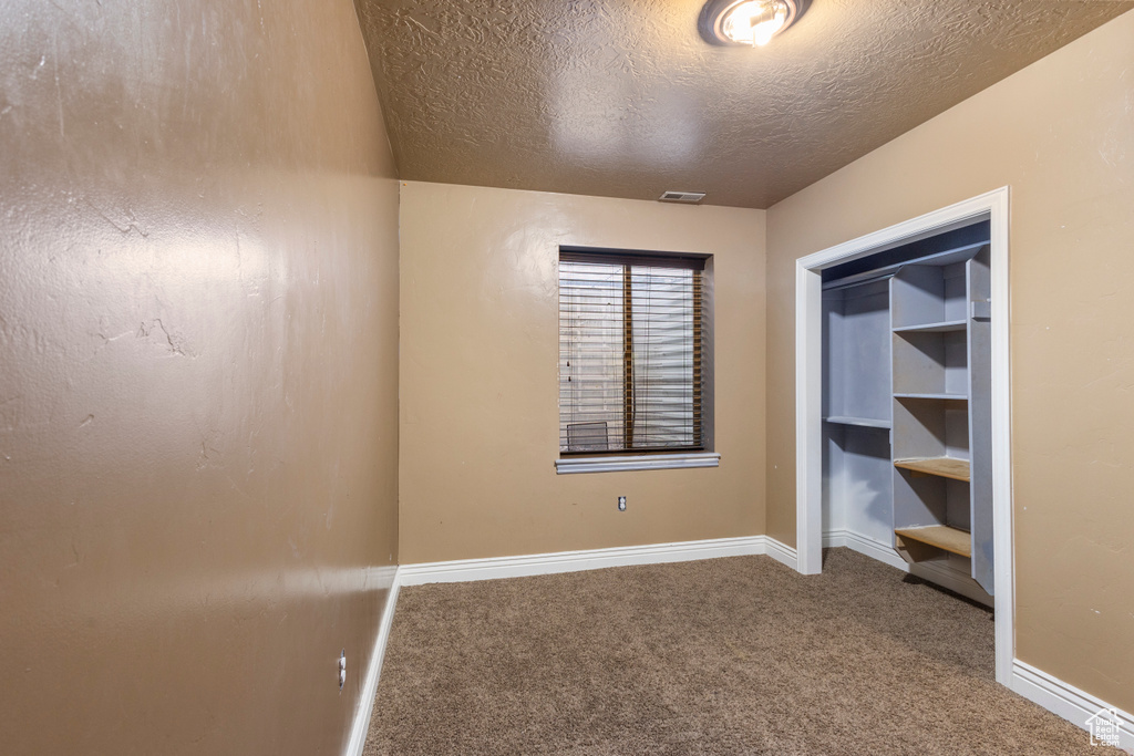 Unfurnished bedroom with carpet floors and a textured ceiling