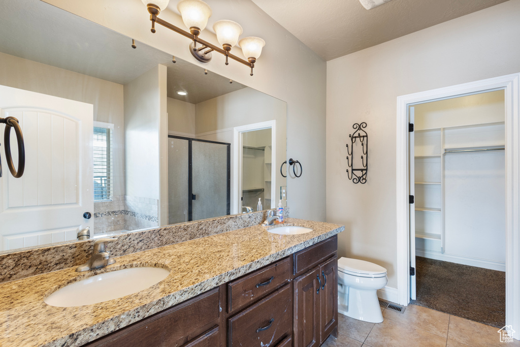 Bathroom featuring vanity, toilet, an enclosed shower, and tile patterned flooring