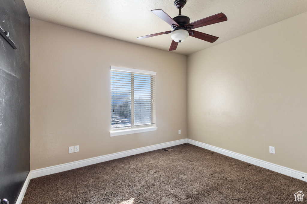 Carpeted spare room featuring ceiling fan