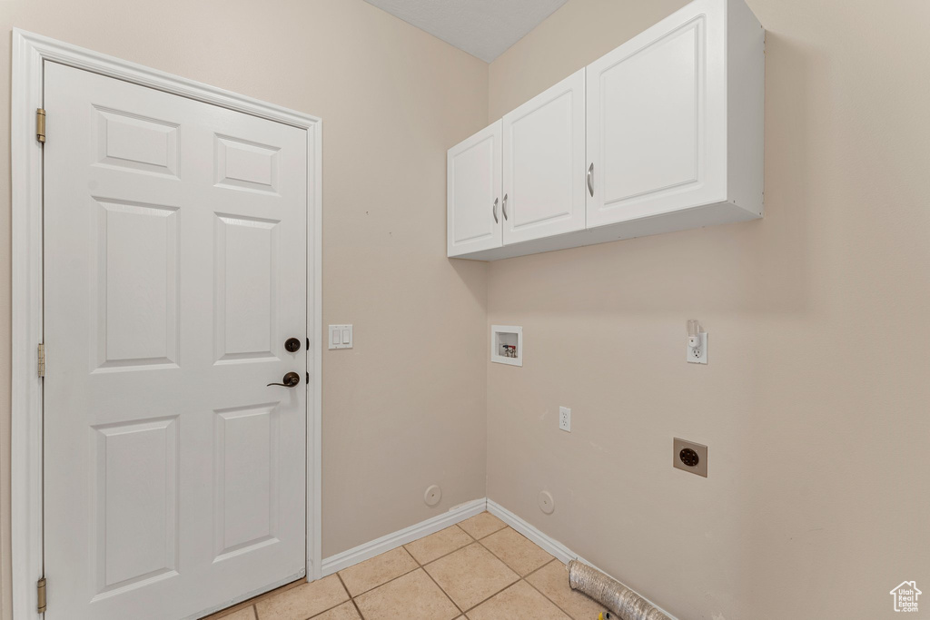 Washroom featuring hookup for an electric dryer, gas dryer hookup, cabinet space, light tile patterned flooring, and washer hookup