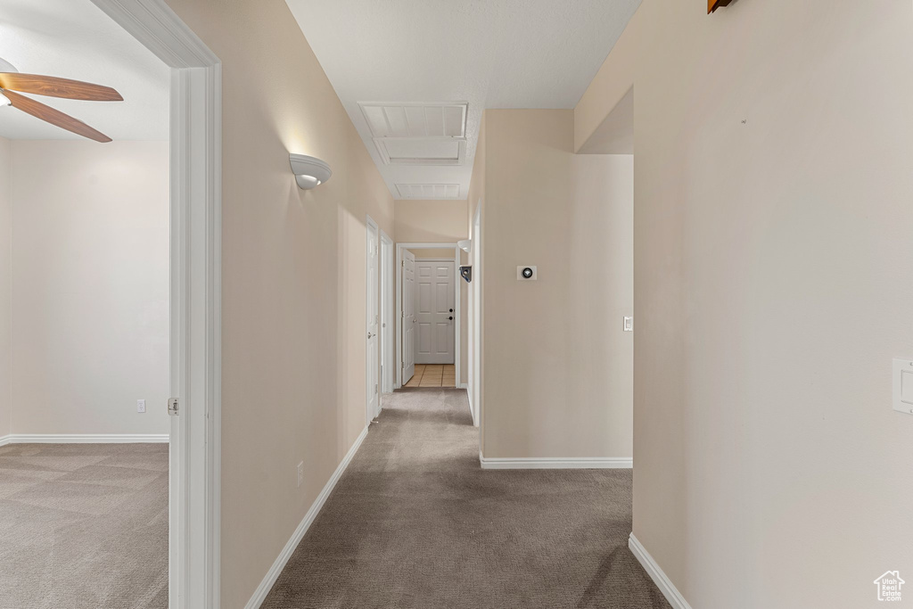 Corridor featuring carpet floors, attic access, and baseboards