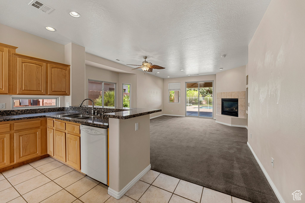Kitchen featuring dishwasher, a sink, open floor plan, light carpet, and a peninsula