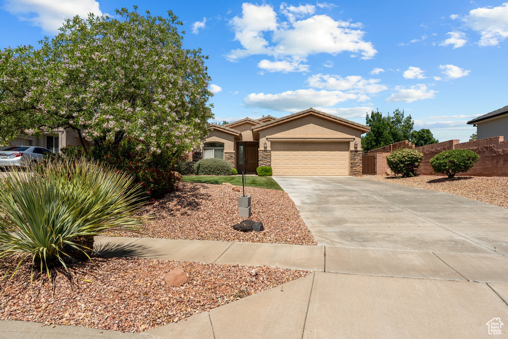 View of front facade with concrete driveway, an attached garage, stucco siding, and stone siding