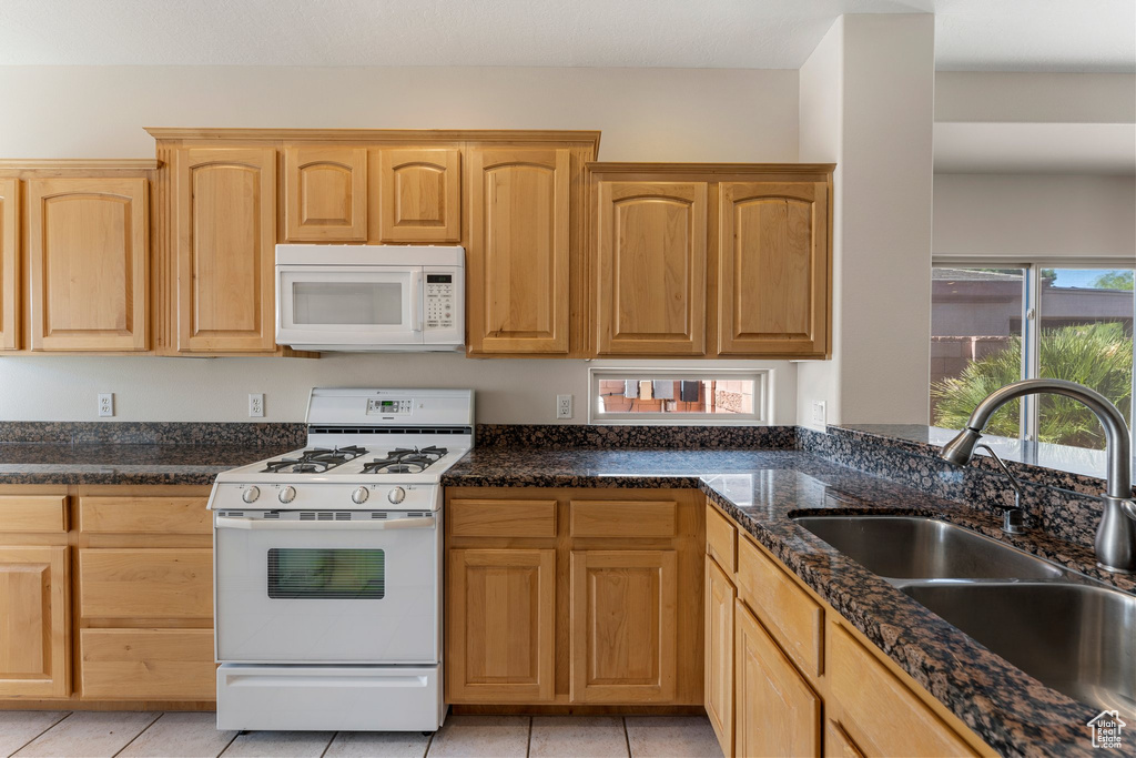 Kitchen with white appliances, a sink, healthy amount of natural light, and light brown cabinetry