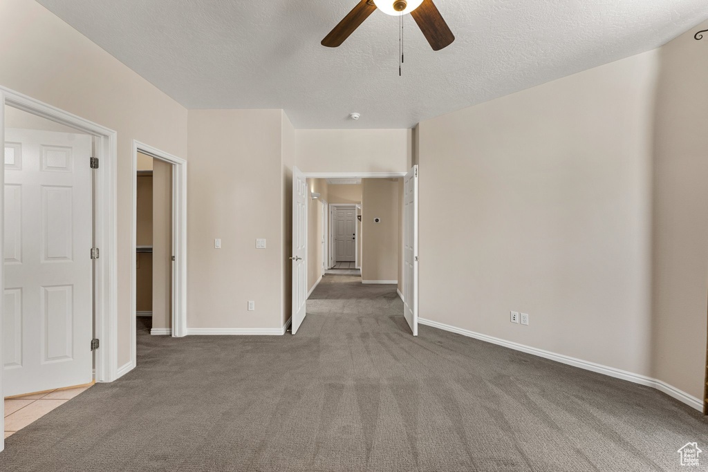 Carpeted spare room featuring ceiling fan, baseboards, and a textured ceiling