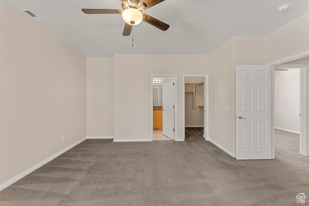 Unfurnished bedroom featuring carpet floors, a walk in closet, and baseboards