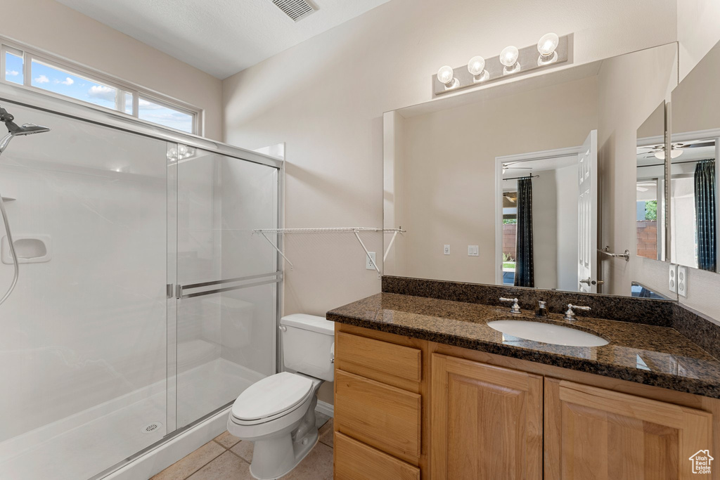 Bathroom with toilet, vanity, a stall shower, and tile patterned flooring