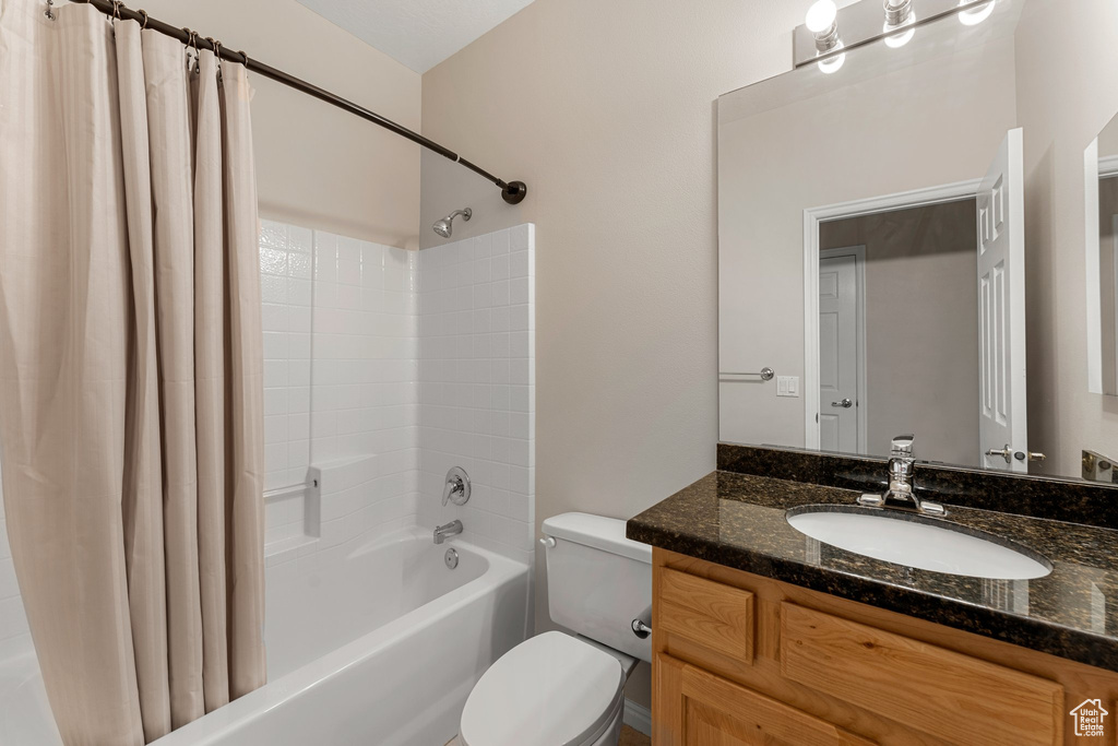 Bathroom featuring shower / tub combo with curtain, toilet, and vanity