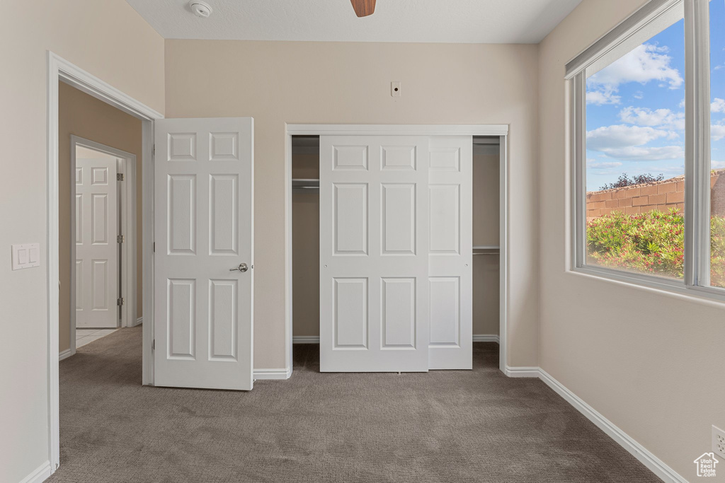 Unfurnished bedroom with carpet flooring, multiple windows, and a closet