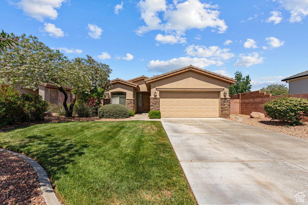Ranch-style home featuring stone siding, stucco siding, driveway, an attached garage, and a tile roof