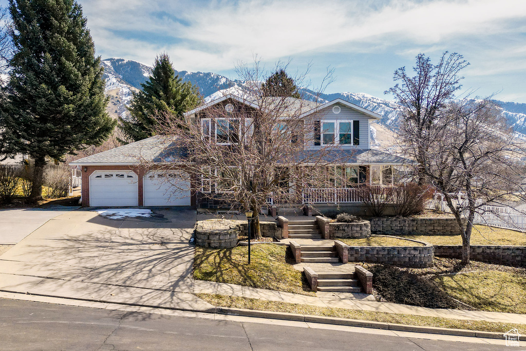 View of front of home featuring driveway, a mountain view, stairway, covered porch, and an attached garage