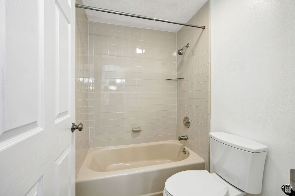 Bathroom with tiled shower / bath and toilet