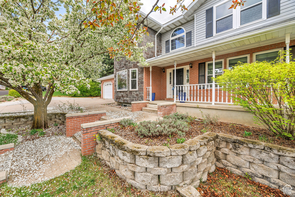 Exterior space featuring covered porch, an attached garage, driveway, and brick siding