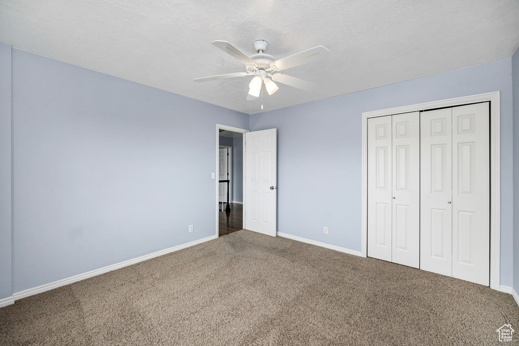 Unfurnished bedroom with carpet, a textured ceiling, ceiling fan, and a closet