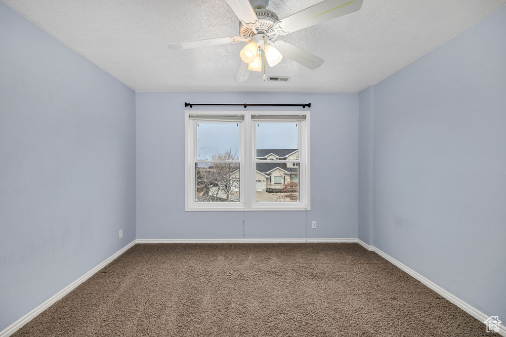 Empty room featuring ceiling fan, carpet floors, and a textured ceiling