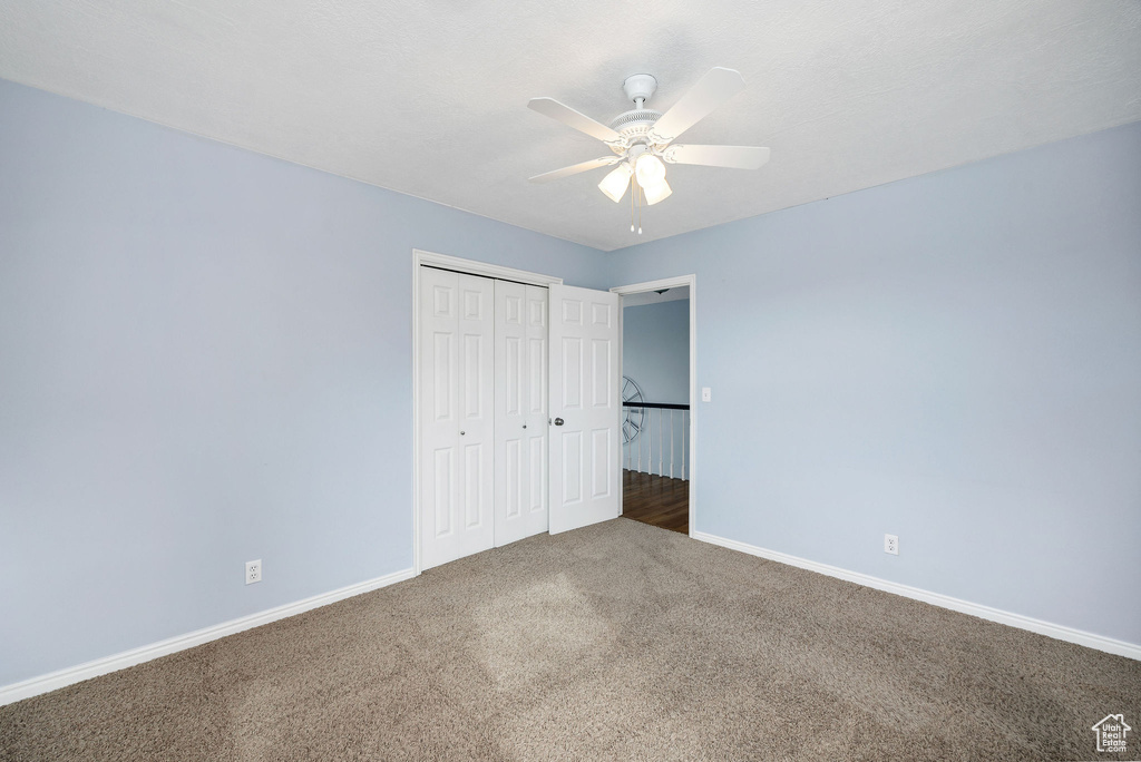 Unfurnished bedroom featuring carpet floors, ceiling fan, and a closet