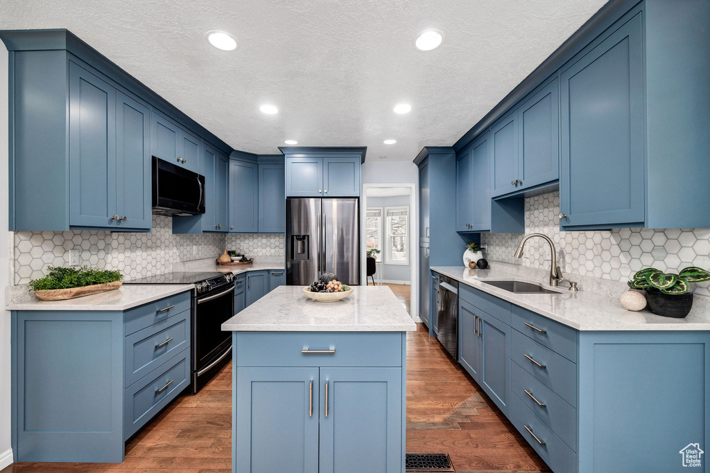 Kitchen with sink, dark wood-type flooring, appliances with stainless steel finishes, a center island, and blue cabinets