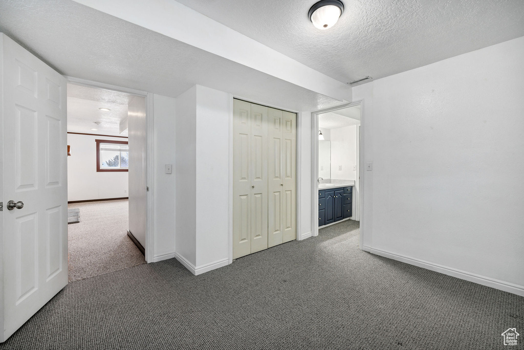 Unfurnished bedroom with a closet, a textured ceiling, and dark colored carpet