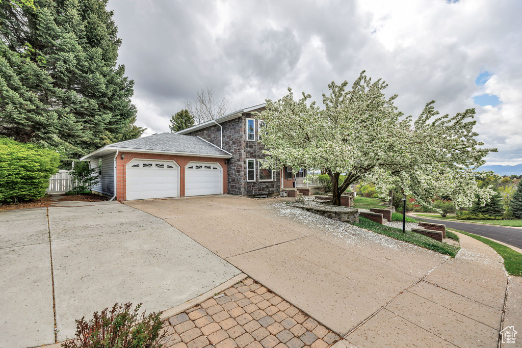 View of front of house with concrete driveway, an attached garage, fence, and stone siding