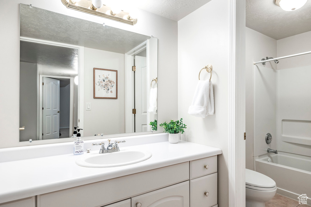 Full bathroom with shower / washtub combination, toilet, a textured ceiling, and vanity