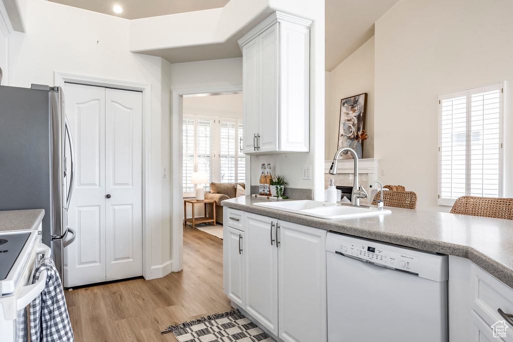 Kitchen featuring sink, white cabinets, white appliances, and light wood-type flooring