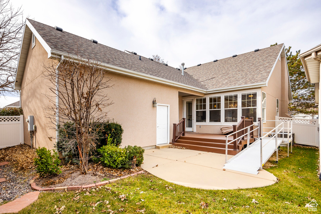 Rear view of property featuring a sunroom, a patio area, and a lawn