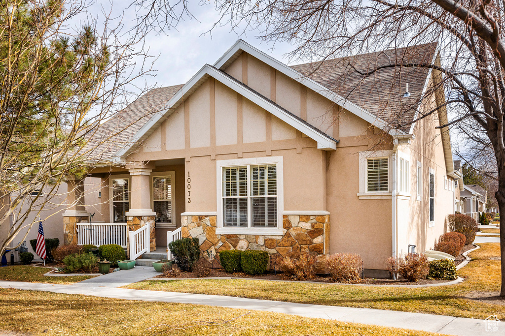English style home with covered porch and a front lawn