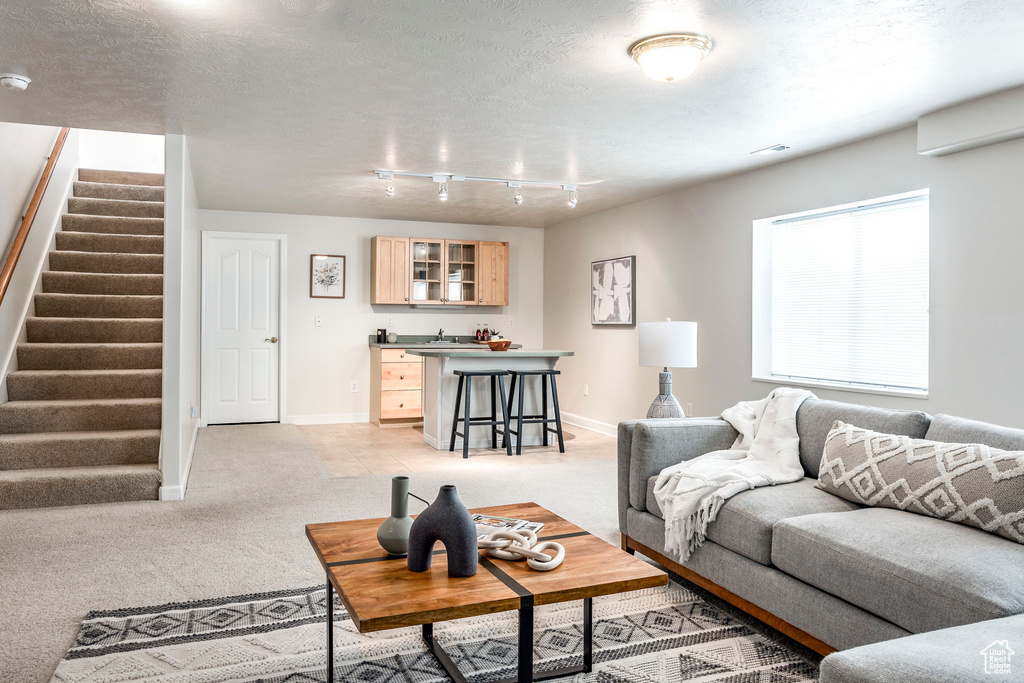 Living room featuring light carpet, a textured ceiling, and a wall mounted AC