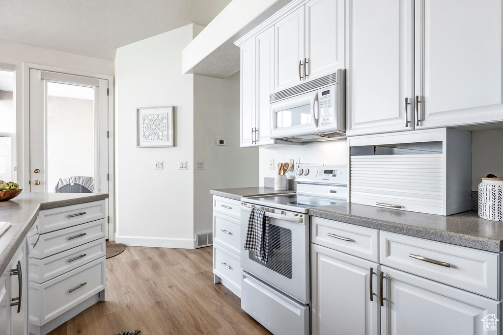 Kitchen featuring white cabinetry, white appliances, and light hardwood / wood-style flooring