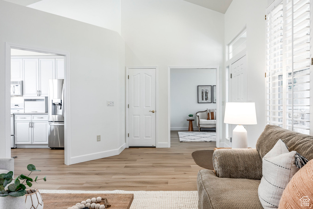 Living room with a towering ceiling and light hardwood / wood-style flooring