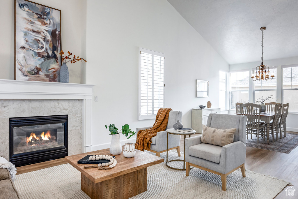 Living room featuring a premium fireplace, lofted ceiling, a healthy amount of sunlight, and light hardwood / wood-style floors