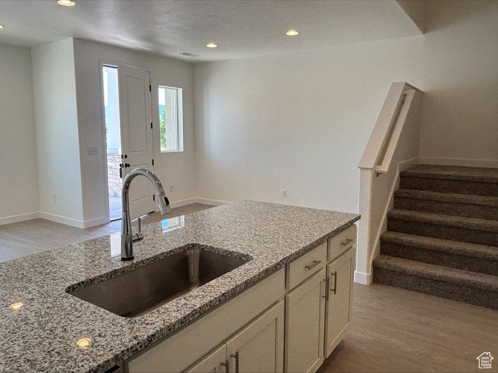 Kitchen featuring light wood-style flooring, light stone countertops, recessed lighting, and white cabinets