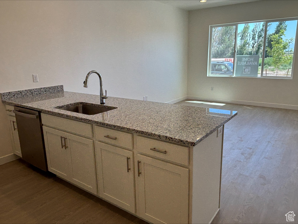 Kitchen featuring dishwasher, dark wood-style flooring, a peninsula, light stone countertops, and white cabinetry