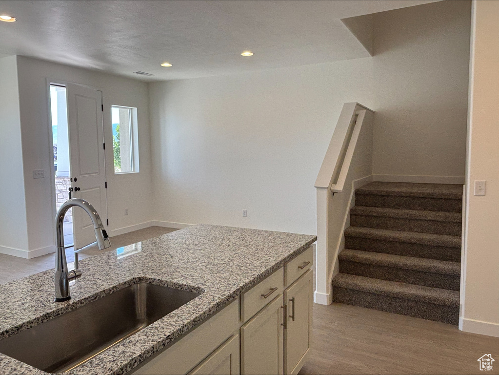 Kitchen with light stone countertops, light wood-style flooring, recessed lighting, and white cabinetry