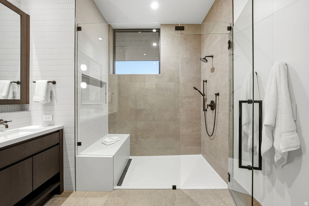 Full bathroom featuring walk in shower, vanity, and tile walls