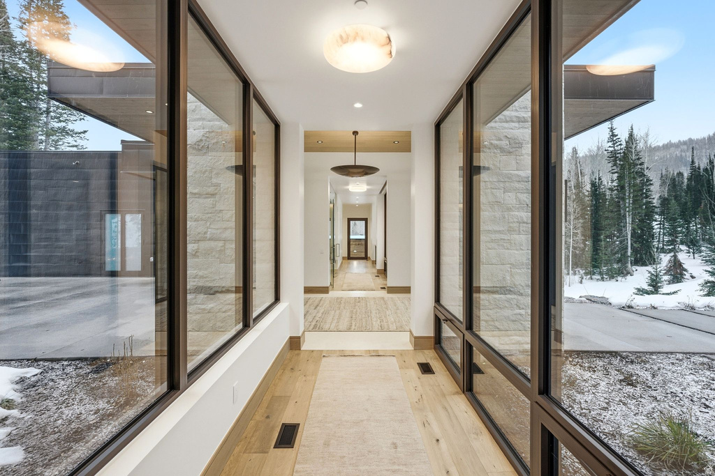 Corridor with a wall of windows and light wood-style floors