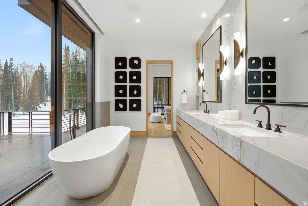 Bathroom with a freestanding tub, double vanity, recessed lighting, and light tile patterned flooring