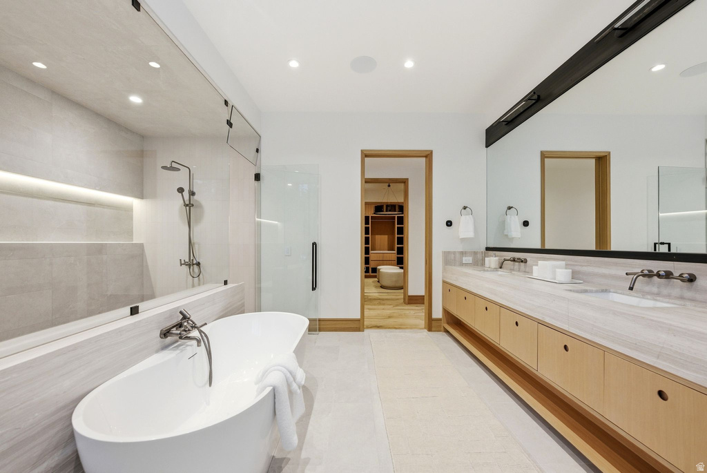 Bathroom with a stall shower, a walk in closet, double vanity, a freestanding bath, and light tile patterned floors