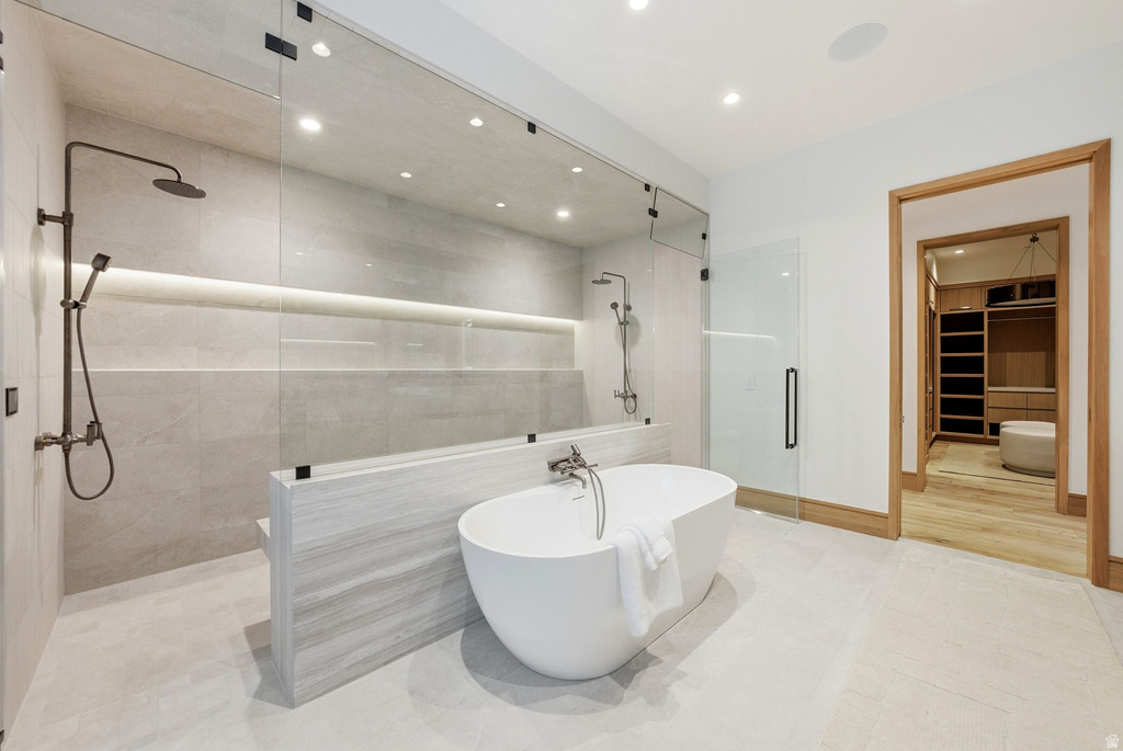Bathroom with a shower stall, a walk in closet, tile patterned flooring, a freestanding bath, and recessed lighting