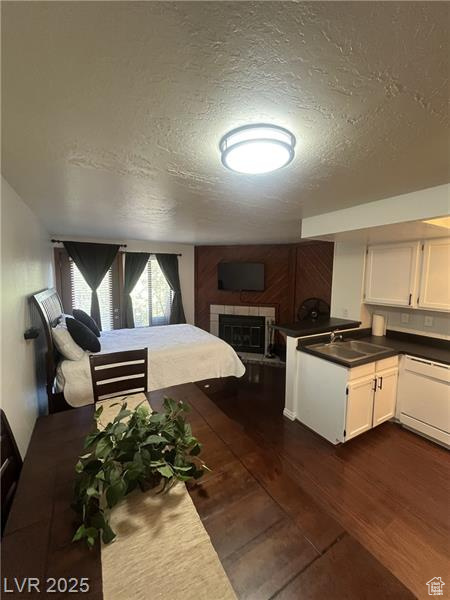 Kitchen with a textured ceiling, white cabinetry, dark countertops, and dark wood-type flooring