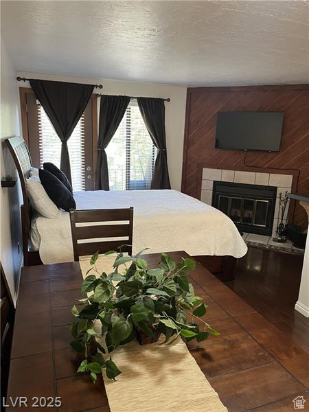 Bedroom featuring a tile fireplace and wood finished floors