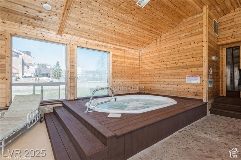 Miscellaneous room featuring lofted ceiling, a hot tub, wood ceiling, wood walls, and carpet floors