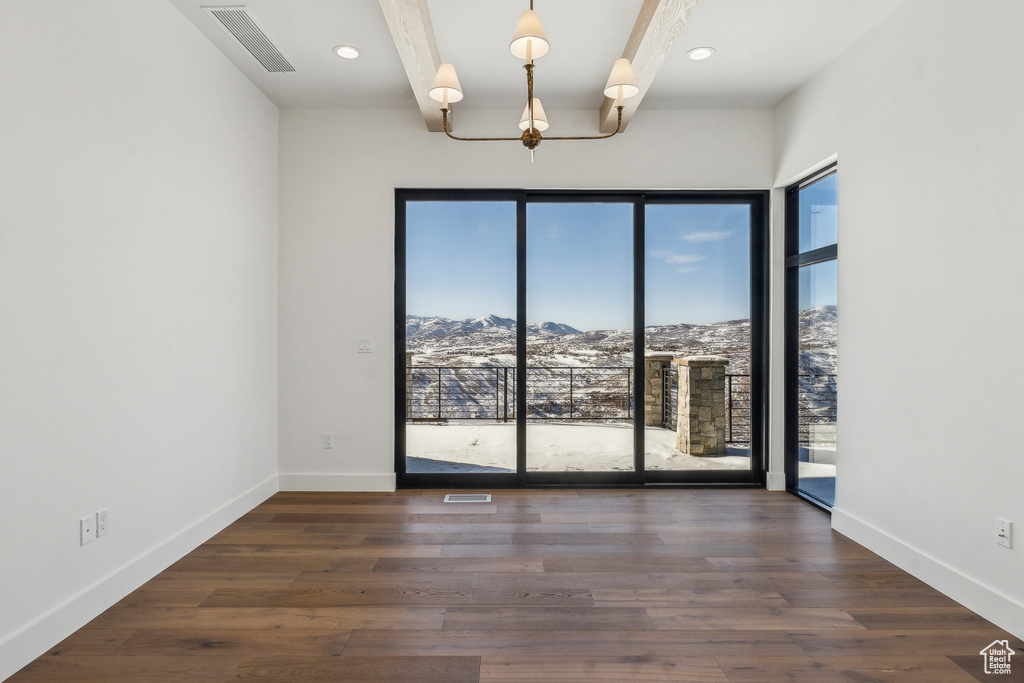 Spare room with a mountain view, wood finished floors, a chandelier, and recessed lighting